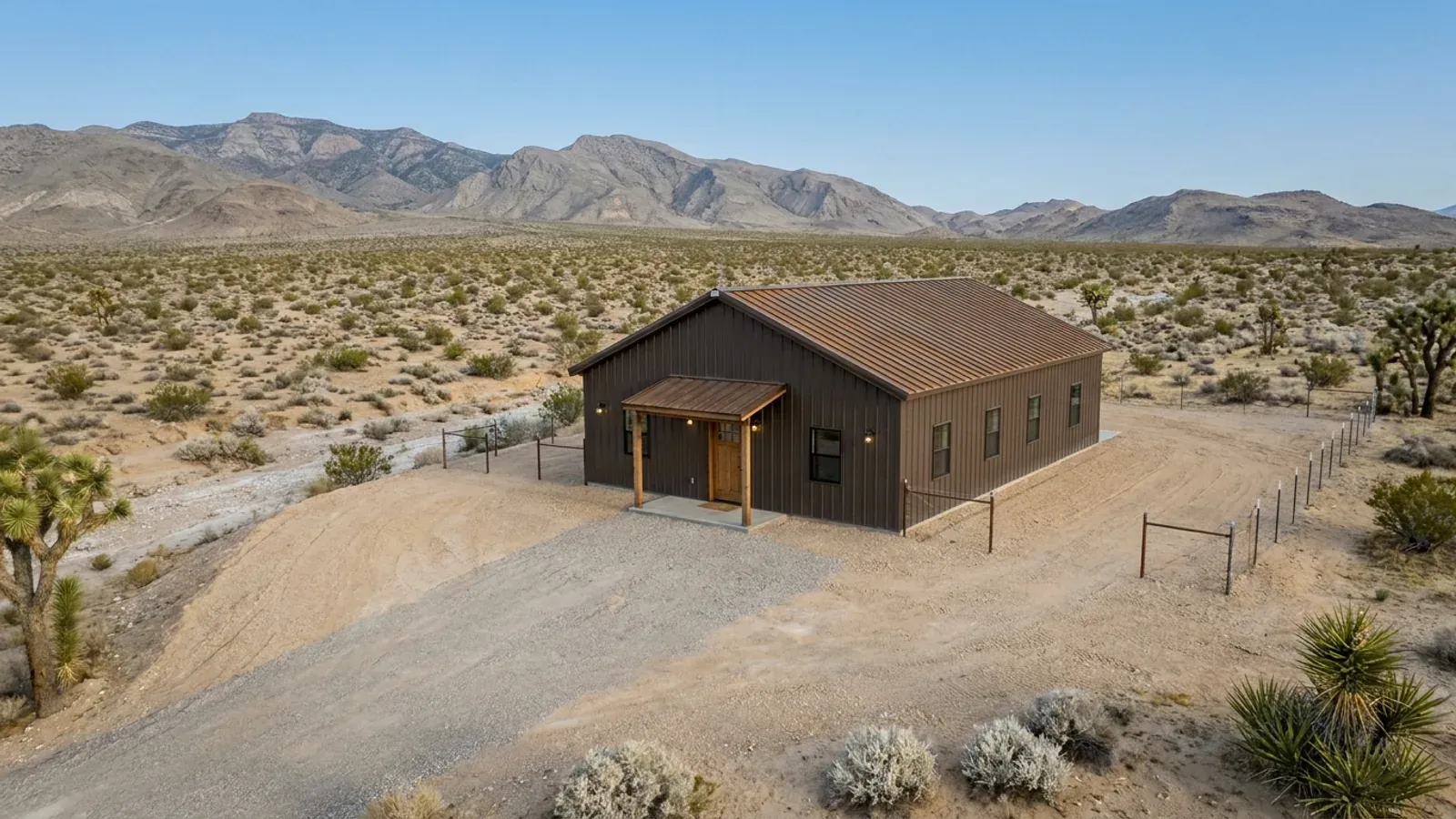 A compact 30x40 barndominium sized like a starter home, with a covered entry porch, in open desert with a few Joshua trees nearby.